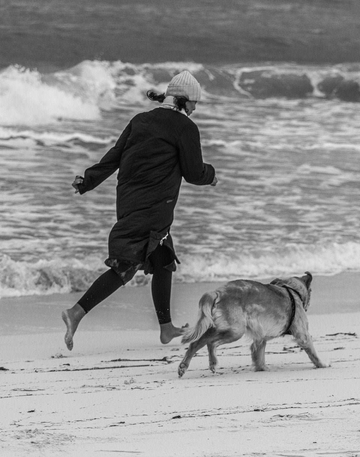 Woman running on beach with golden retriever — active dog lifestyle